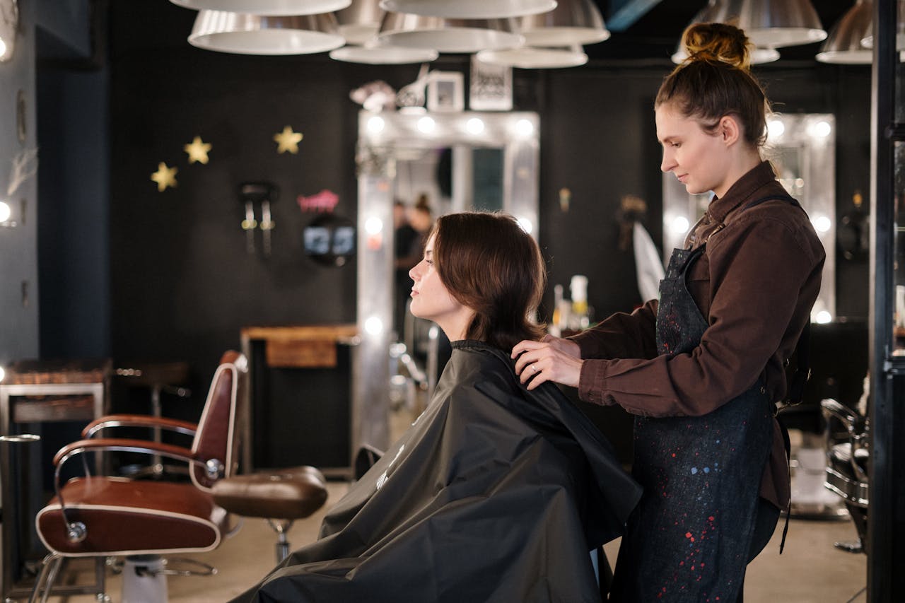 A hairstylist trims a clients hair in a modern salon setting, capturing a moment of focus.